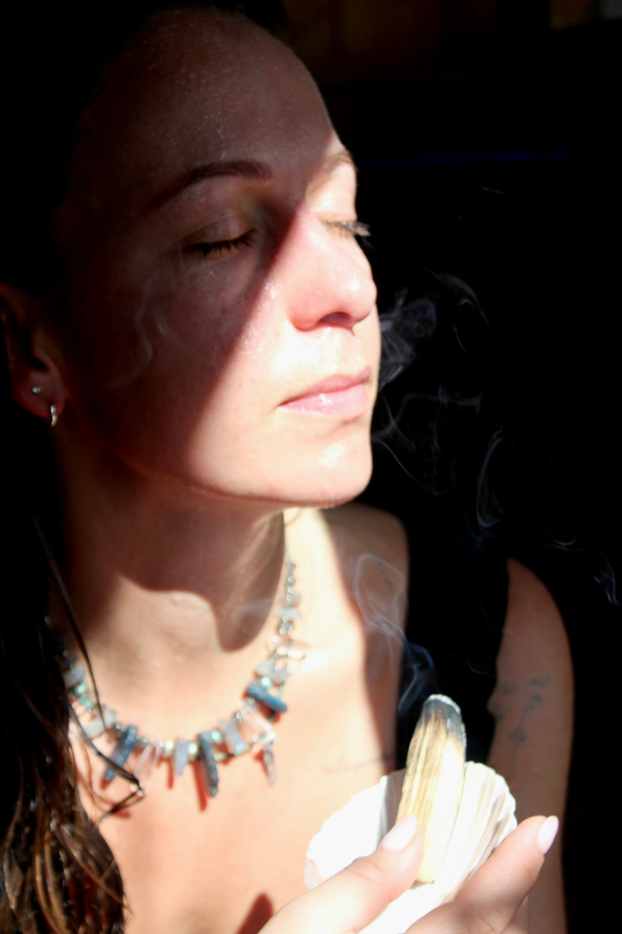 A woman holding a smoking shell during a quiet purification ritual